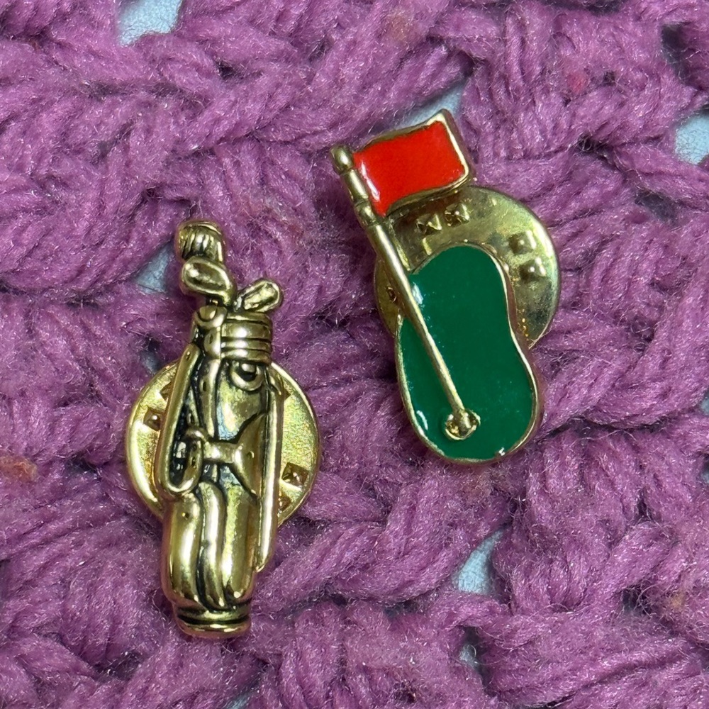 Cute little golf pins one with a flag on green and a golf club bag